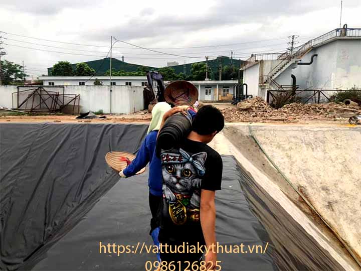 Hoạt động kéo trải bạt nhựa HDPE được thực hiện khẩn trương tại công trình hồ chứa nước thải ở Bắc Ninh
